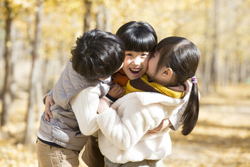 Three children playing in autumn woods