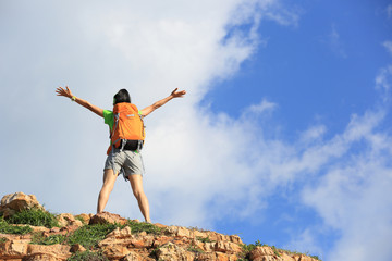 Obraz premium young woman backpacker climbing to mountain peak