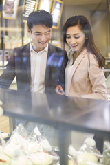 Young couple choosing cakes in bakery