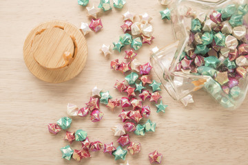 colorful of paper fold  stars spilling out from the bottle  to wood surface