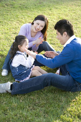 Naklejka na ściany i meble Young family playing in the park