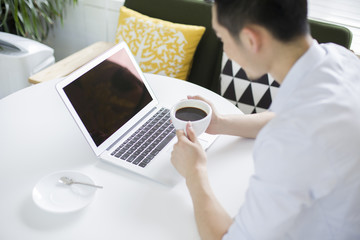 Happy young man using laptop in coffee shop
