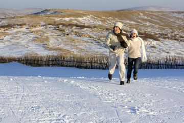 Young man and young woman running in the snow