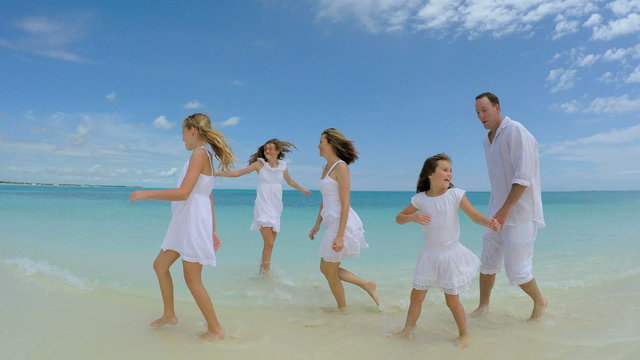 Smiling Caucasian family walking barefoot on the beach 
