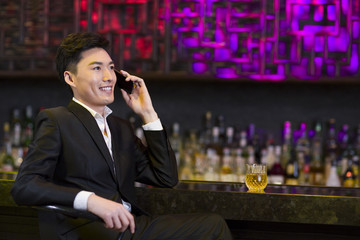 Young man talking on the phone at bar