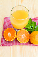 Glass of orange juice with orange slice on soft wooden background