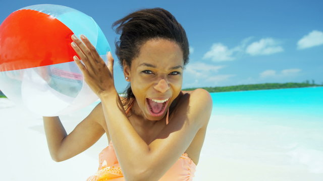 Young African American female wearing bikini holding beach ball