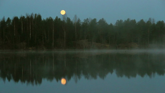 Foggy river in early morning with full moon