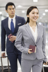 Young business person walking in airport with suitcases