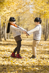 Two children playing in autumn woods