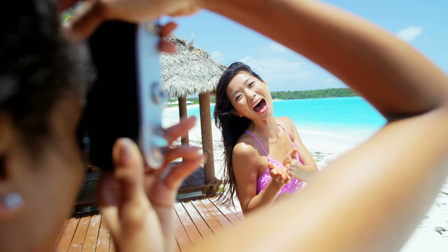 Beautiful young African American Asian Chinese girls taking selfie on beach 