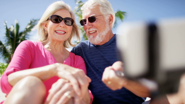 Retired Caucasian couple taking a selfie at a beach resort