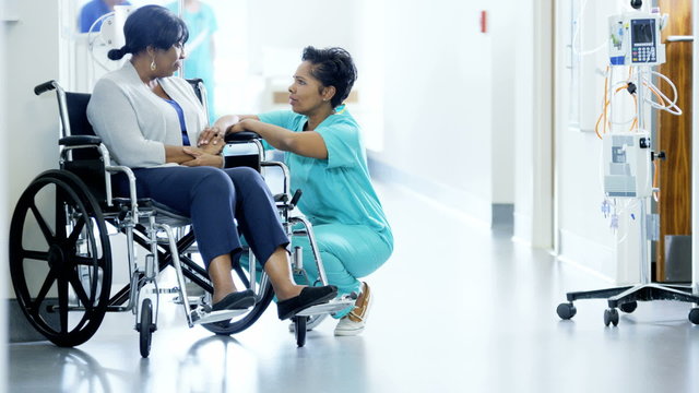 African American female staff and disabled patient consult in medical centre 