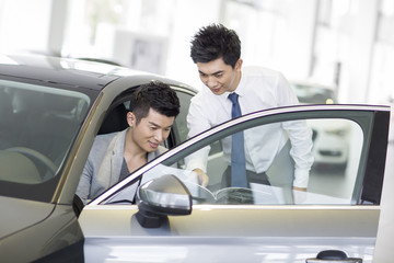 Young man choosing car in showroom