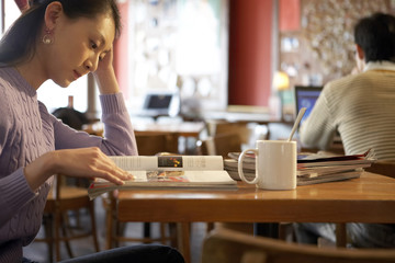 Young Woman Sitting In Cafe With Books