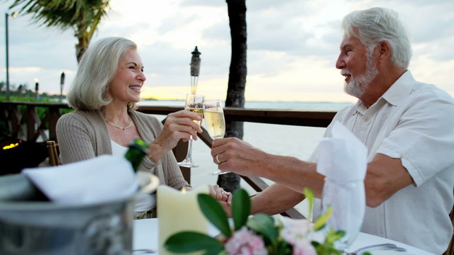 Retired Caucasian senior couple enjoying evening dinner at luxury beach hotel