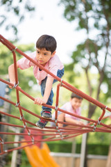 Little boy climbing on the rope at playground