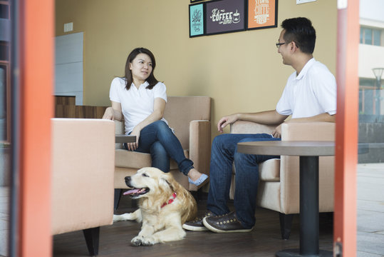 Asian Couple At Cafe With Their Pet Dog