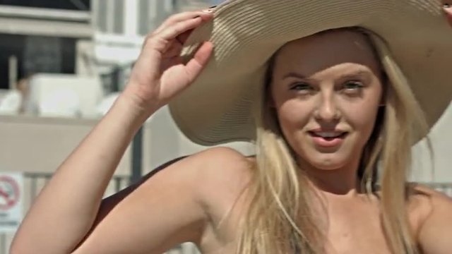 Beautiful woman laughs and poses while wearing a big straw hat.  Close up.  Originally recorded in 4K, UHD.