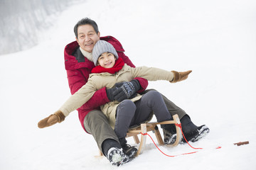 Grandfather and grandson sliding on a sled