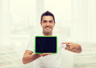 smiling man showing tablet pc blank screen at home
