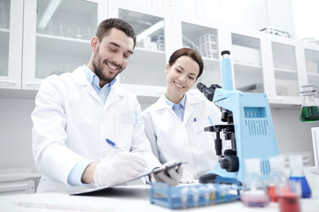 Fototapeta premium scientists with clipboard and microscope in lab