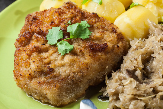Fried pork schnitzel served with boiled potatoes and fried sauer
