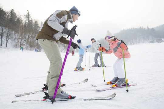 Young parents teaching children to ski