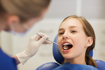 female dentist checking patient girl teeth