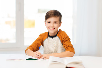 smiling student boy writing to notebook at home