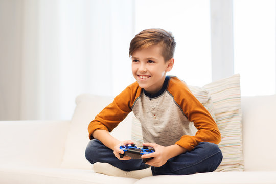 happy boy with joystick playing video game at home