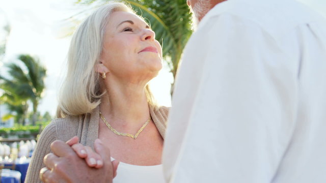 Happy senior couple dancing together at a tropical vacation resort