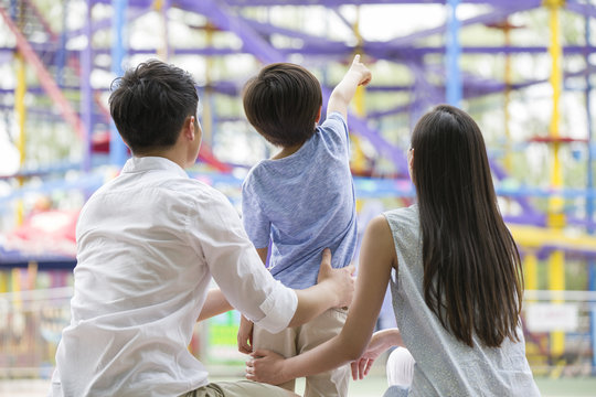 Happy Young Family Playing In Amusement Park