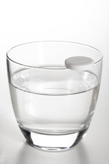 glass filled with water and a vitamin pill