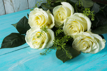 Fresh spring summer white ivory roses flowers on turquoise painted wooden planks. Mother's day greetings. Birthday congratulations. Selective focus. Postcard with beautiful flowers 