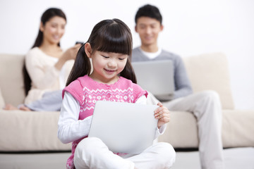 Young family using electronic gadgets in living room