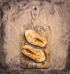 Two delicious grilled salmon steak with spices on a cutting board on wooden rustic background top view close up