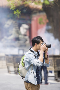 Side view of man taking picture with camera outdoors