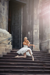 Love to see her dance. Soft focus shot of a ballerina posing on her knee standing on the stairs of an old building © serhiibobyk