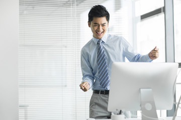 Fototapeta premium Cheerful young businessman using computer in office