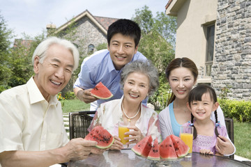 Three generation family eating watermelon