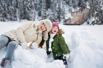 Fototapeta na wymiar Portrait of mother and child playing with the snow outdoors