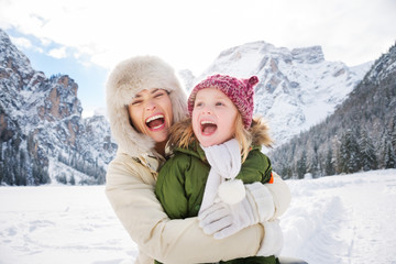 Mother and child hugging outdoors in front of snowy mountains