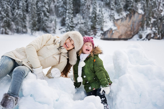 Portrait of mother and child playing with the snow outdoors