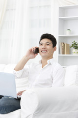 Young man using laptop and phone at home