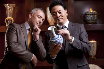 Mature businessmen admiring an antique Chinese vase