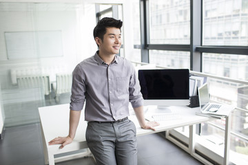 Young businessman looking through window in office