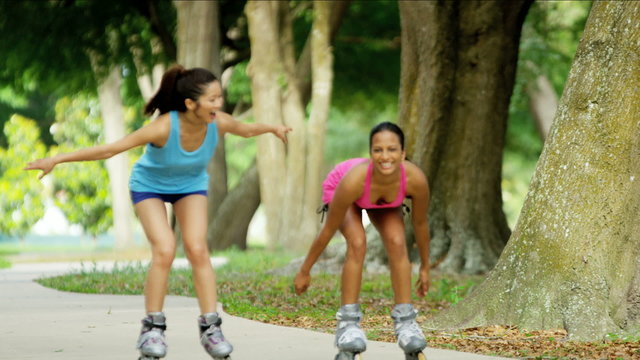Young happy multi ethnic American girls enjoying roller skating outdoor