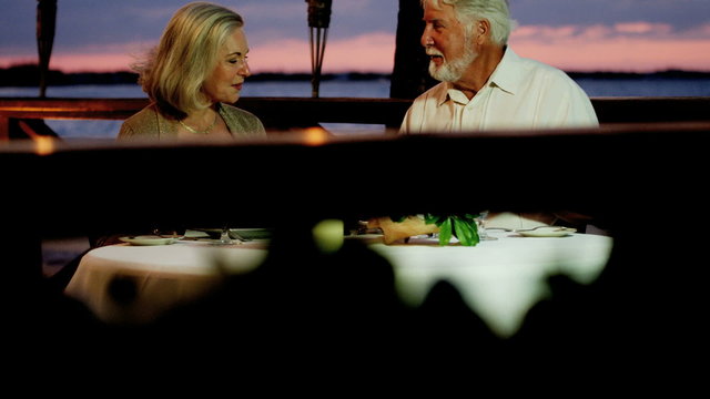 Loving senior Caucasian couple enjoying romantic beachfront dining 