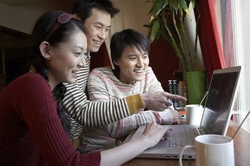 Young People With Coffee Cups Looking At Laptop Computer